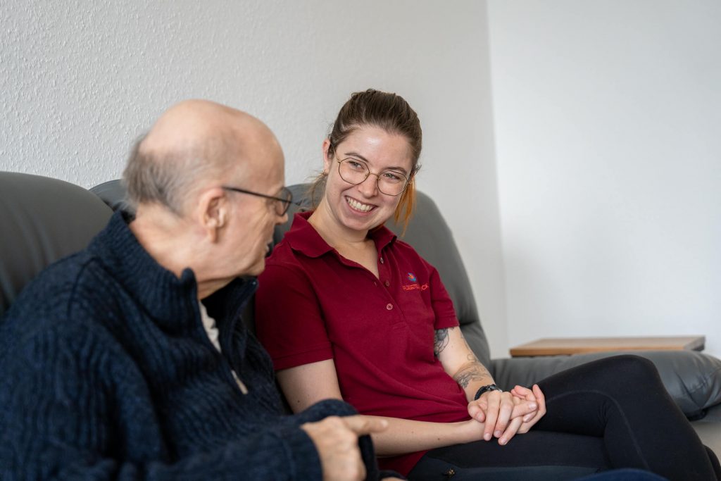 Mitarbeiterin Anna im Gespräch mit einem Kunden der Senioren-WG Springbachhöfe Paderborn, im Wohnzimmer unserer WG.